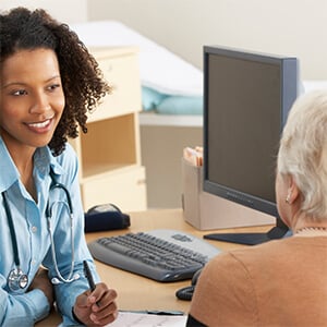 Female doctor smiling and speaking to an elderly female patient.