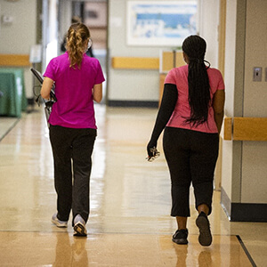 Two women walking down a hallway in a hospital.